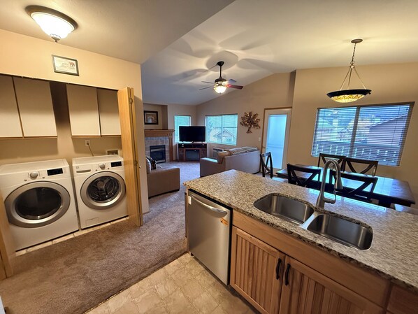 A compact kitchen with built-in appliances, a dining area with a table and chairs, and a living room with a sofa and fireplace.