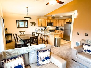 A modern kitchen with wooden cabinets, stainless steel appliances, and a dining area with a table and chairs.