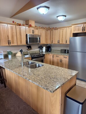 A kitchen with wooden cabinets, a granite countertop, stainless steel appliances, and a built-in sink.