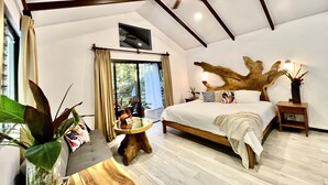 Quarto espaçoso com uma cama grande, um ventilador de teto, cabeceira de madeira e vista por uma janela ampla.
