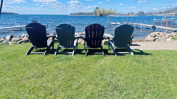 Three Adirondack chairs facing a lake with a dock and pier in the background. - Charming Fall Cabin on Lake Mille Lacs; Relax, Fish & Watch the Sunset (Isle)