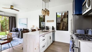 A modern kitchen with a central island, white cabinetry, and a built-in oven.
