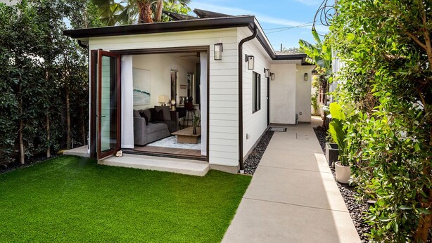 A modern house with a glass door leading to a living area, a well-maintained lawn, and a pathway.