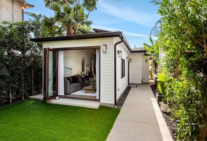 A modern house with a glass door leading to a living area, a well-maintained lawn, and a pathway. - Quiet and Elegant Retreat for 4 Travelers (Culver City)