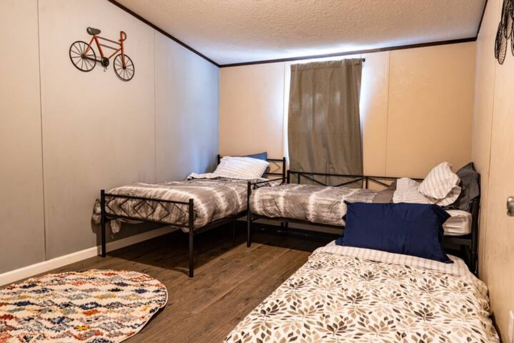 A small, cozy room with two single beds, a patterned rug, and a bicycle illustration on the wall.