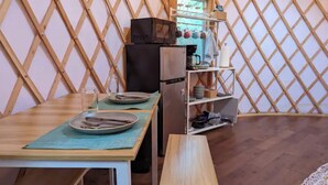 Una cocina compacta con microondas, refrigerador y una alacena con utensilios de cocina.
