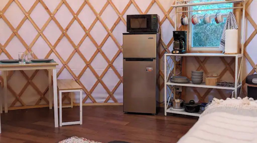 Une cuisine compacte équipée d’un réfrigérateur, d’un four à micro-ondes, d’une machine à café et d’une fenêtre donnant sur un paysage agréable.