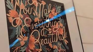 Une œuvre d’art encadrée, portant l’inscription « Vous embellissez tout », le tout agrémenté de motifs floraux.