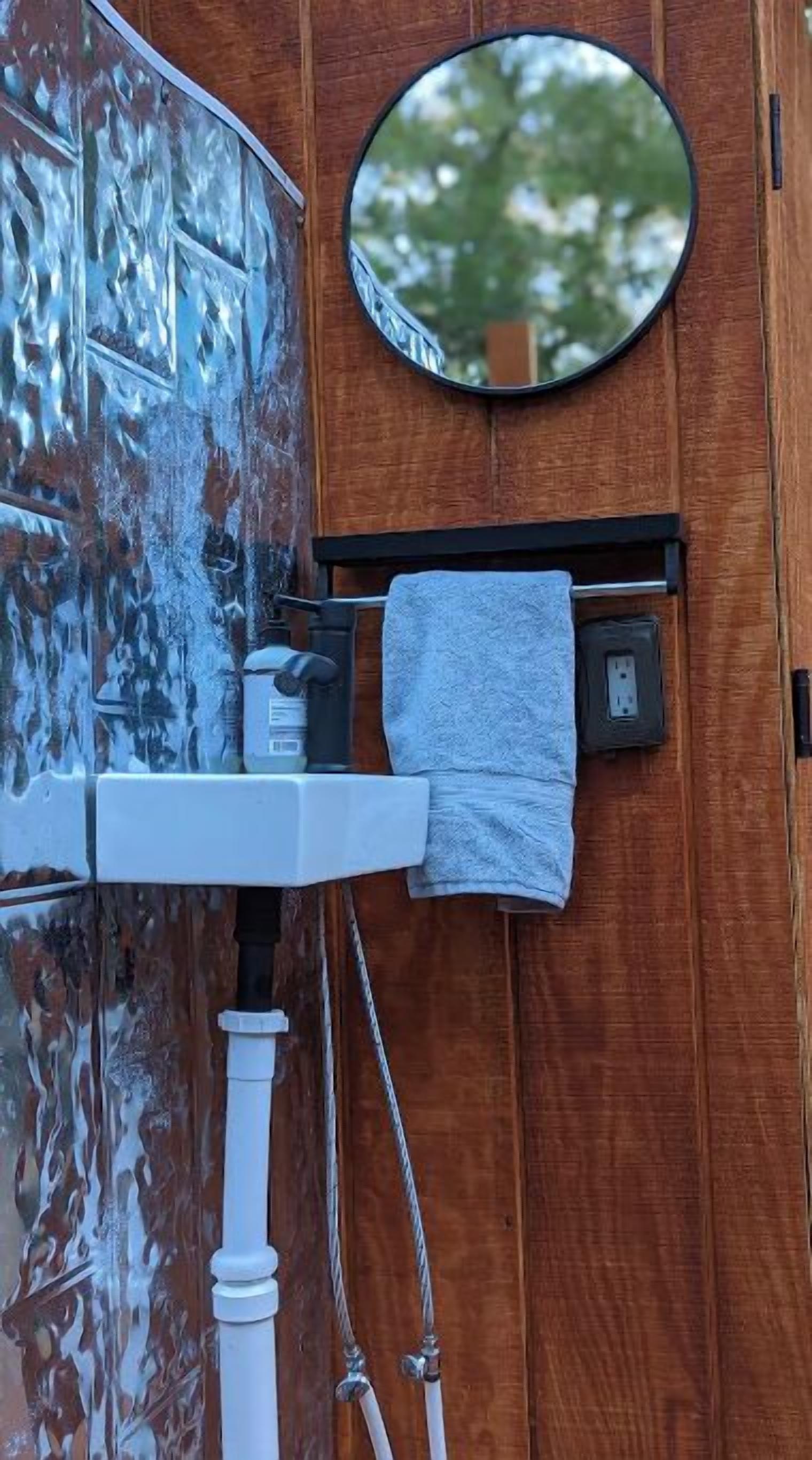 A bathroom with a wooden vanity, a mirror, a towel hanging on a rack, and a window with frost.