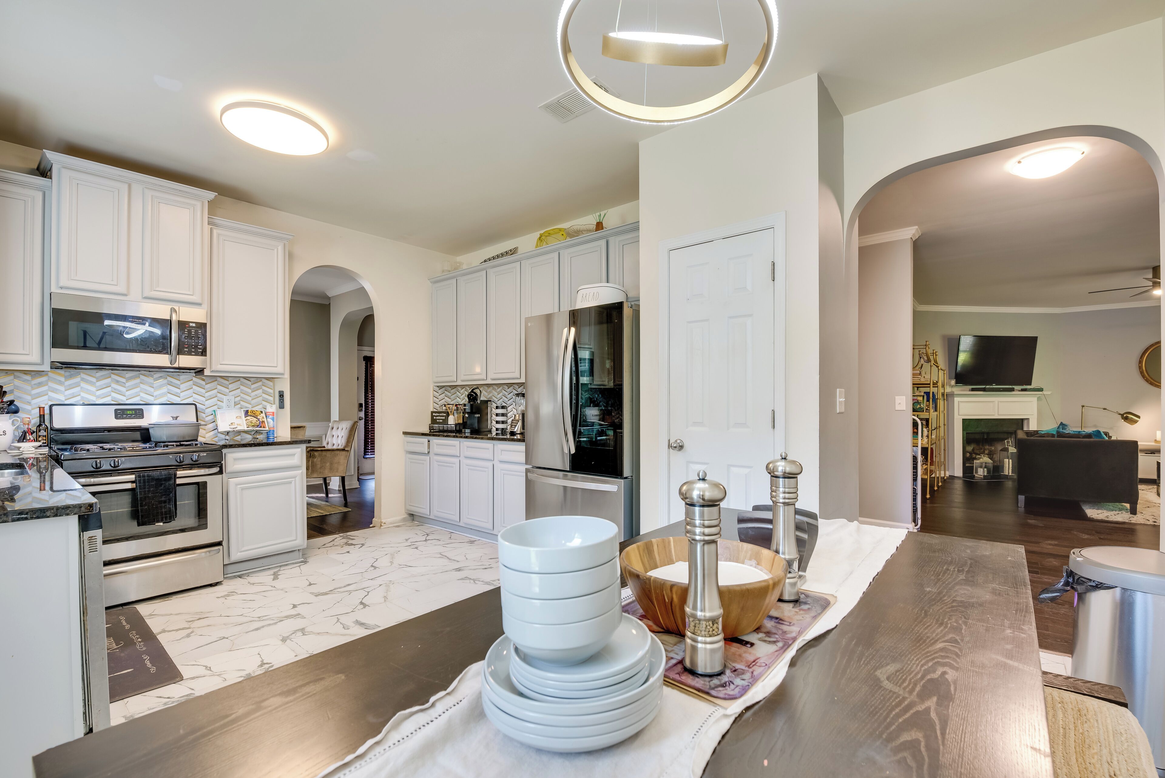 A modern kitchen with white cabinets, stainless steel appliances, and a marble floor.