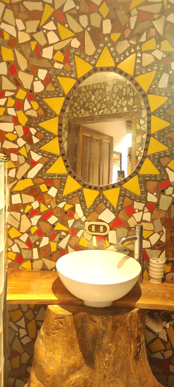 A bathroom with a mosaic tile wall, a wooden vanity, and a round mirror. - Seacret Villa (Cóbano)