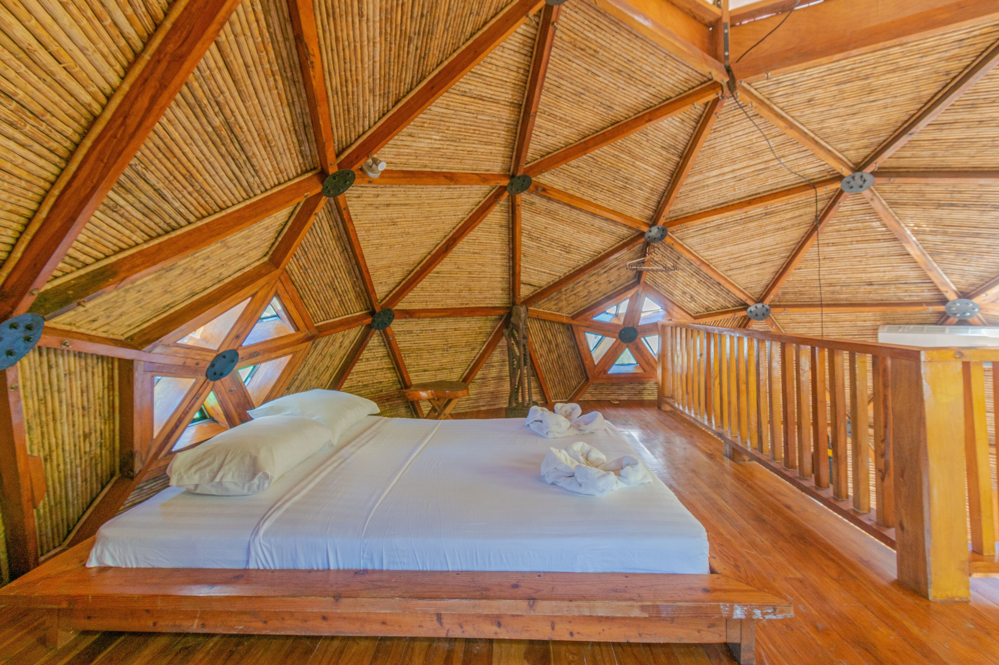 A wooden room with a high ceiling and a bed with white linens.