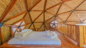 A wooden room with a high ceiling and a bed with white linens.