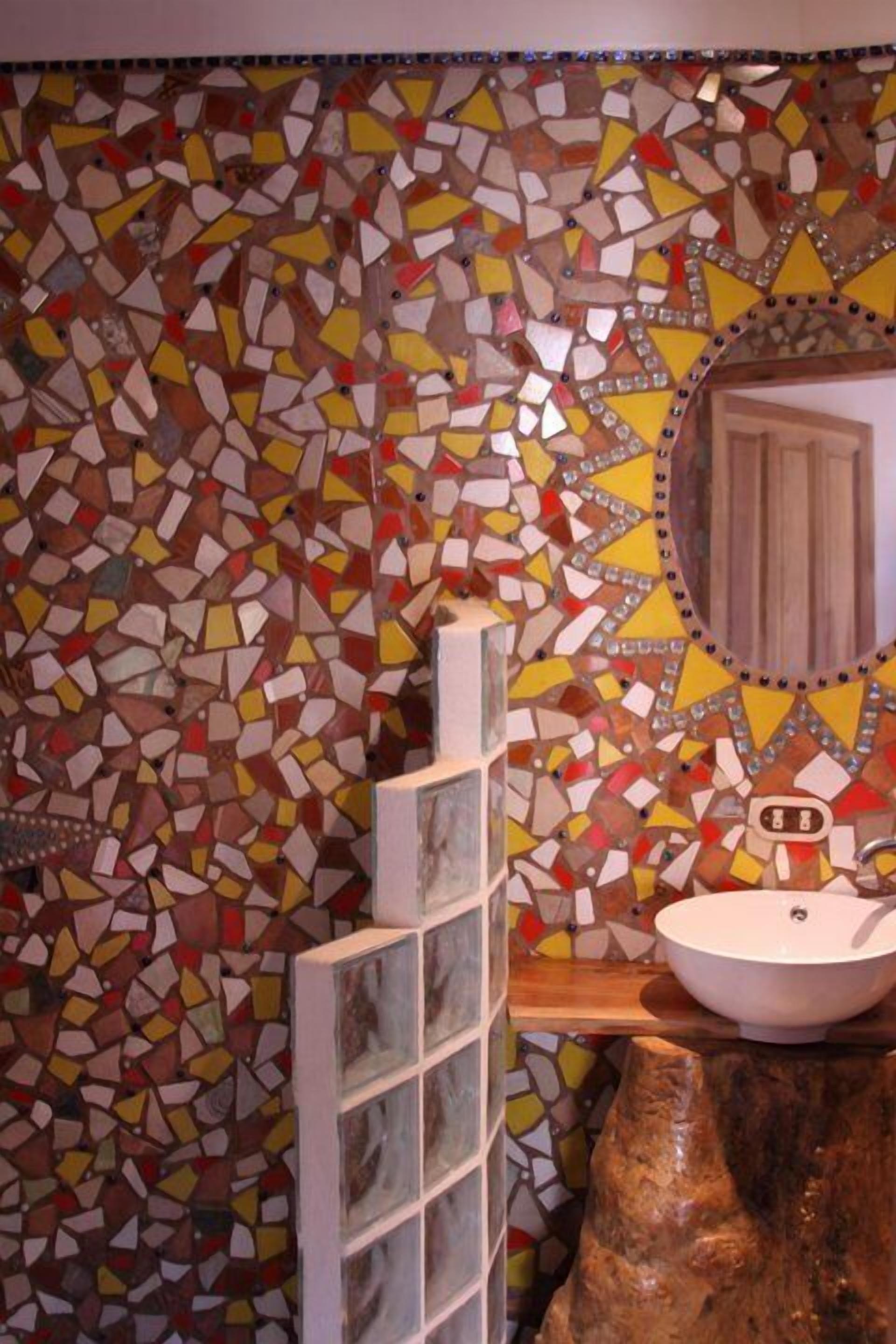 A bathroom with a mosaic tile wall, a wooden vanity, and a sink.