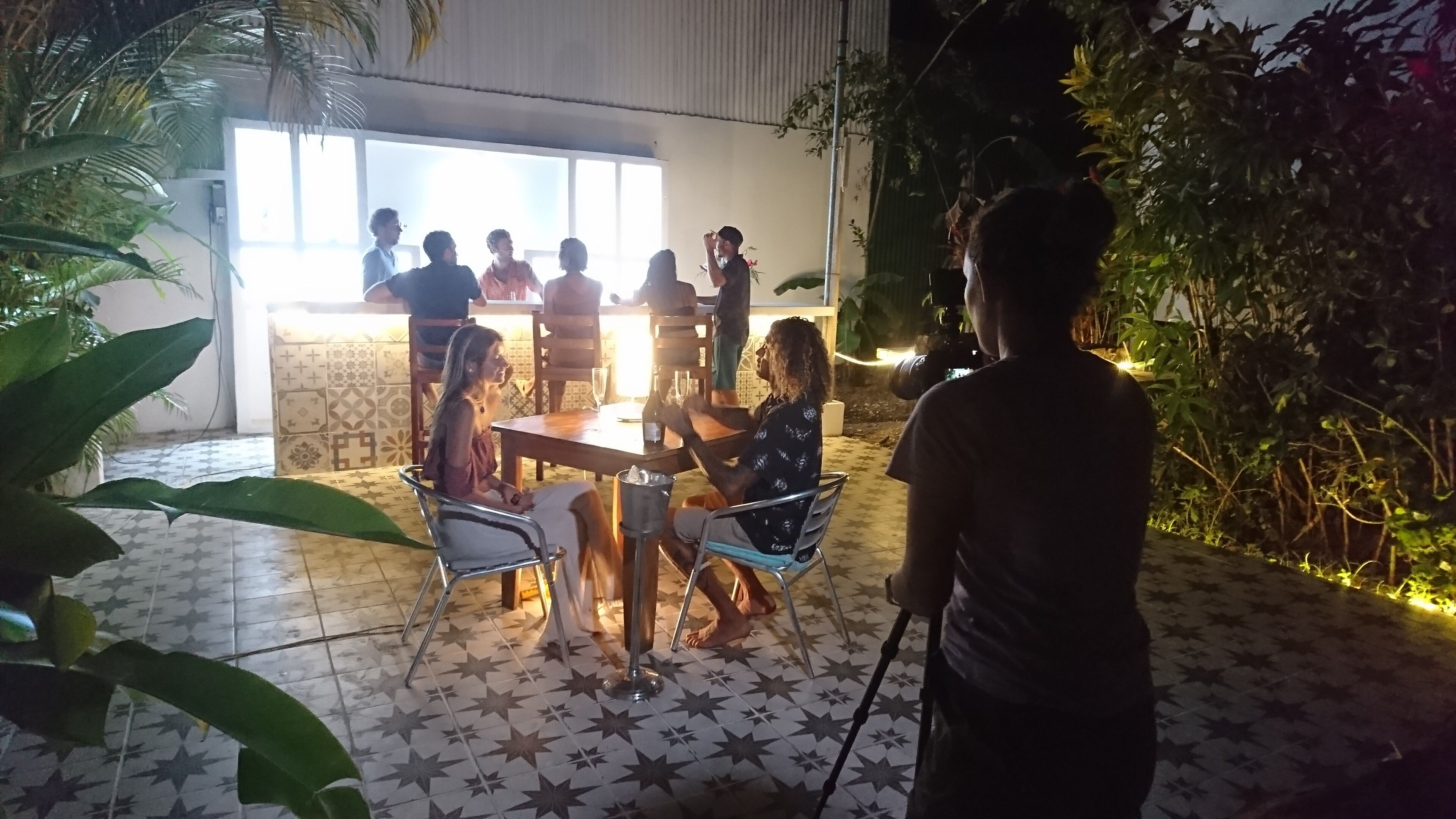 An outdoor dining area with a tiled floor, metal chairs, and a table with chairs.