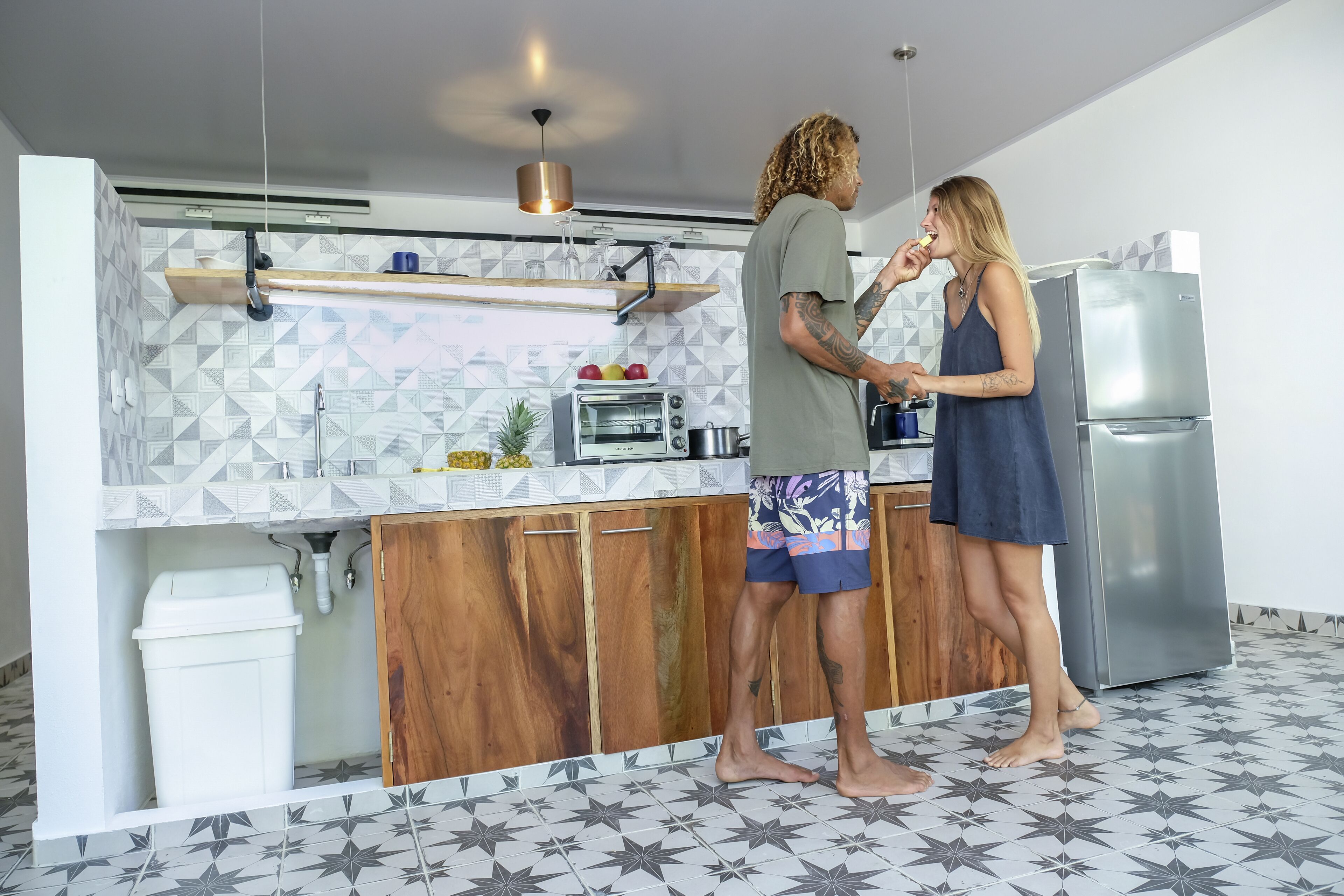 A modern kitchen with a built-in oven, a stainless steel refrigerator, and a wooden cabinet.