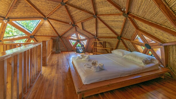 A wooden interior with a bed, wooden railings, and a fan. - Seacret Villa (Cóbano)