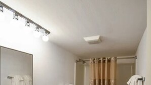 Une salle de bain avec un lavabo, des toilettes et une baignoire. Un rideau de douche et des serviettes sont accrochés au mur.
