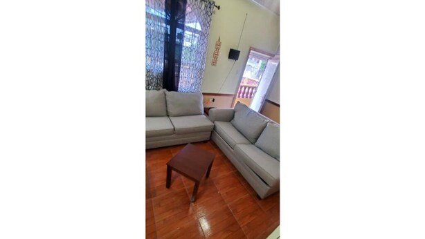 Una sala de estar con dos sofás grises, una mesa de centro de madera y una ventana con cortina.