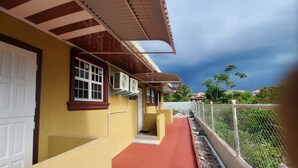 Un bâtiment jaune avec un chemin rouge menant à une entrée fermée par un portail.