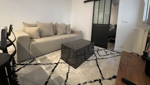 A modern living room with a beige sofa, a black coffee table, and a patterned rug. - Suite Luxueuse Avec Jardin Privatif et Jacuzzi (Paris)
