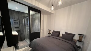 A modern bedroom with a large bed, bedside tables, and a walk-in closet. - Suite Luxueuse Avec Jardin Privatif et Jacuzzi (Paris)