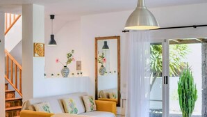 Una sala de estar acogedora con un sofá, una mesita de centro, un espejo grande y una escalera.