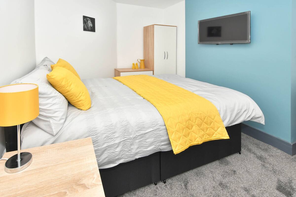 Une chambre à coucher avec un lit, une table de chevet, une armoire et un téléviseur.