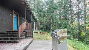 Un pontile in legno conduce a una baita con una griglia per barbecue e posti a sedere all'aperto.