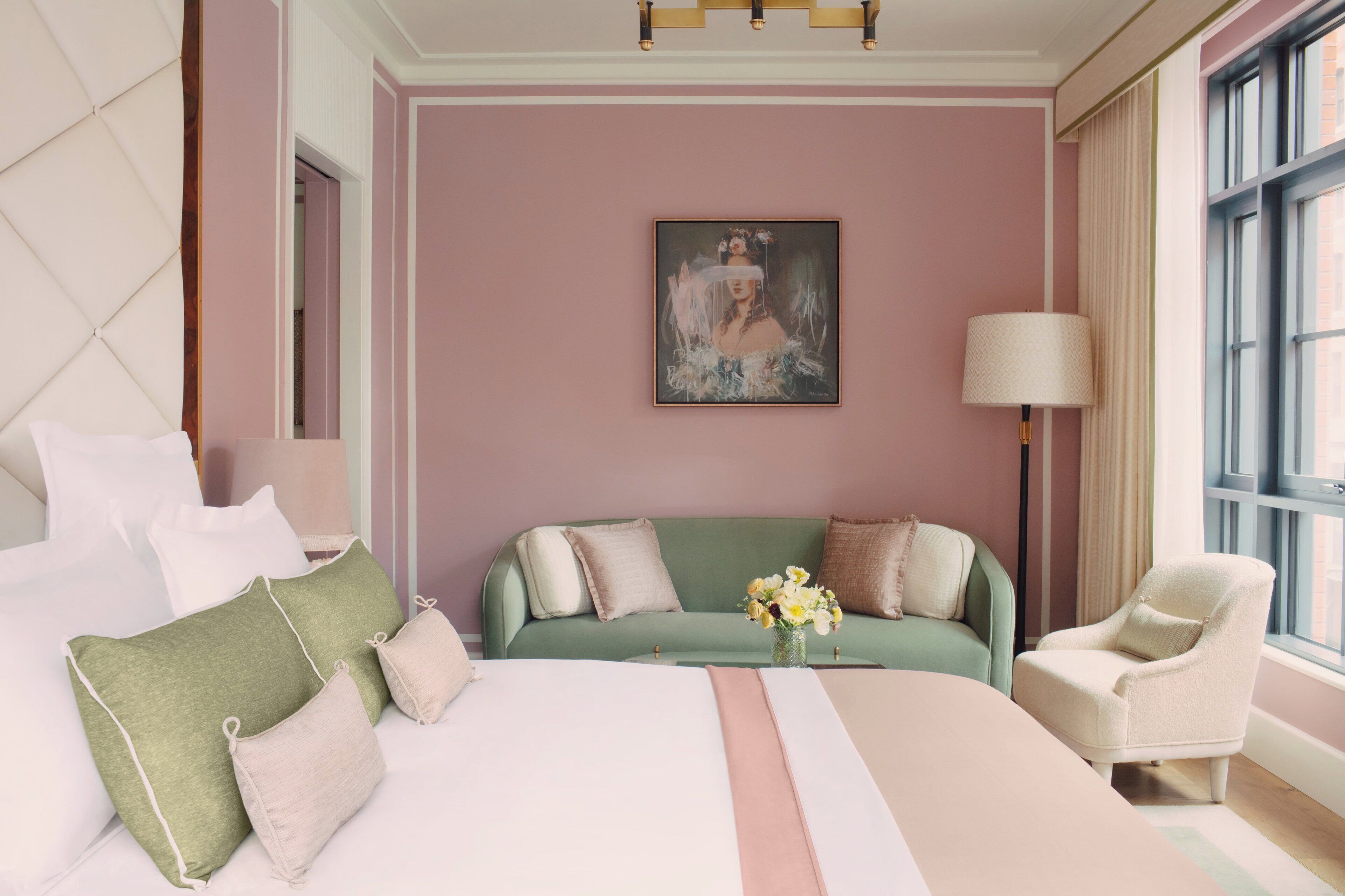 Une chambre à coucher avec un grand lit, un canapé vert, une chaise, une lampe et un tableau au mur.