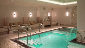 Un área de spa con piscina, asientos y una pared de mármol.