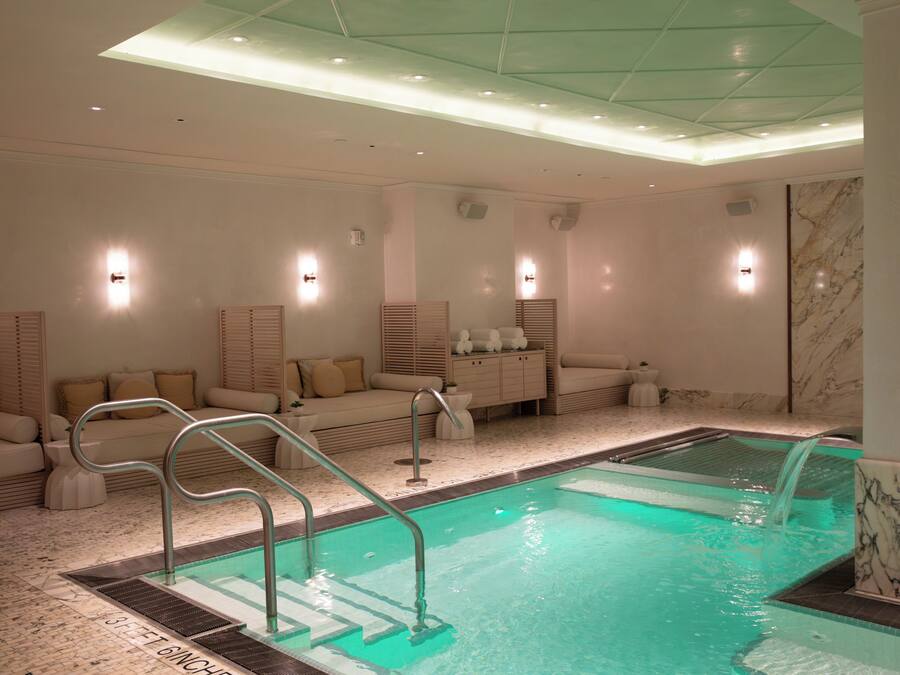 A spa area with a pool, seating, and a marble wall.