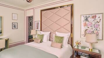 A neatly arranged bedroom with a large bed, a bedside table with a lamp, and framed artwork on the walls.
