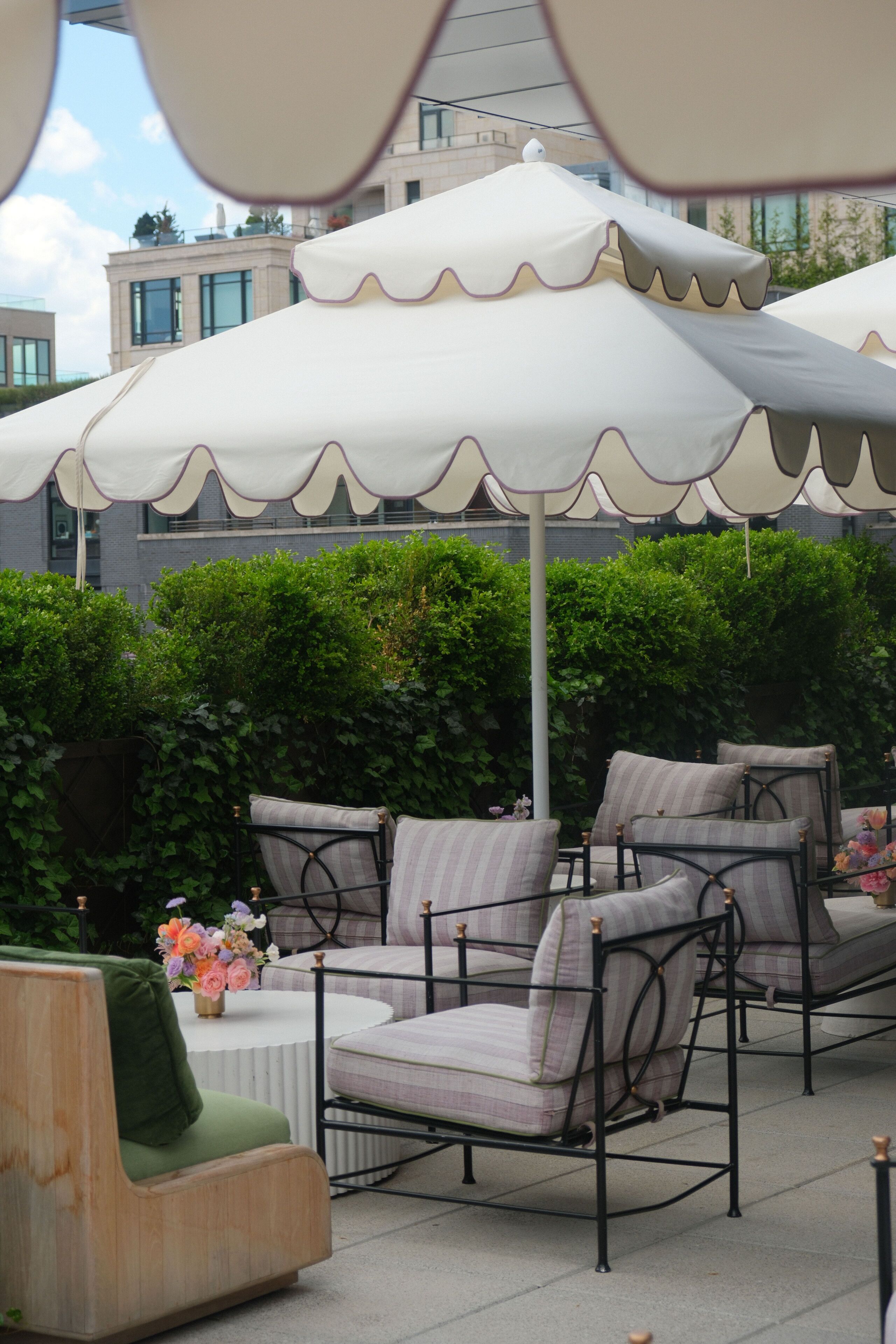 Buiten zitplaatsen met parasols, een ronde tafel en een groene stoel.