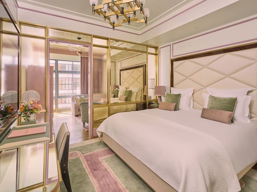 A spacious bedroom with a large bed, a desk with a chair, and a mirror.
