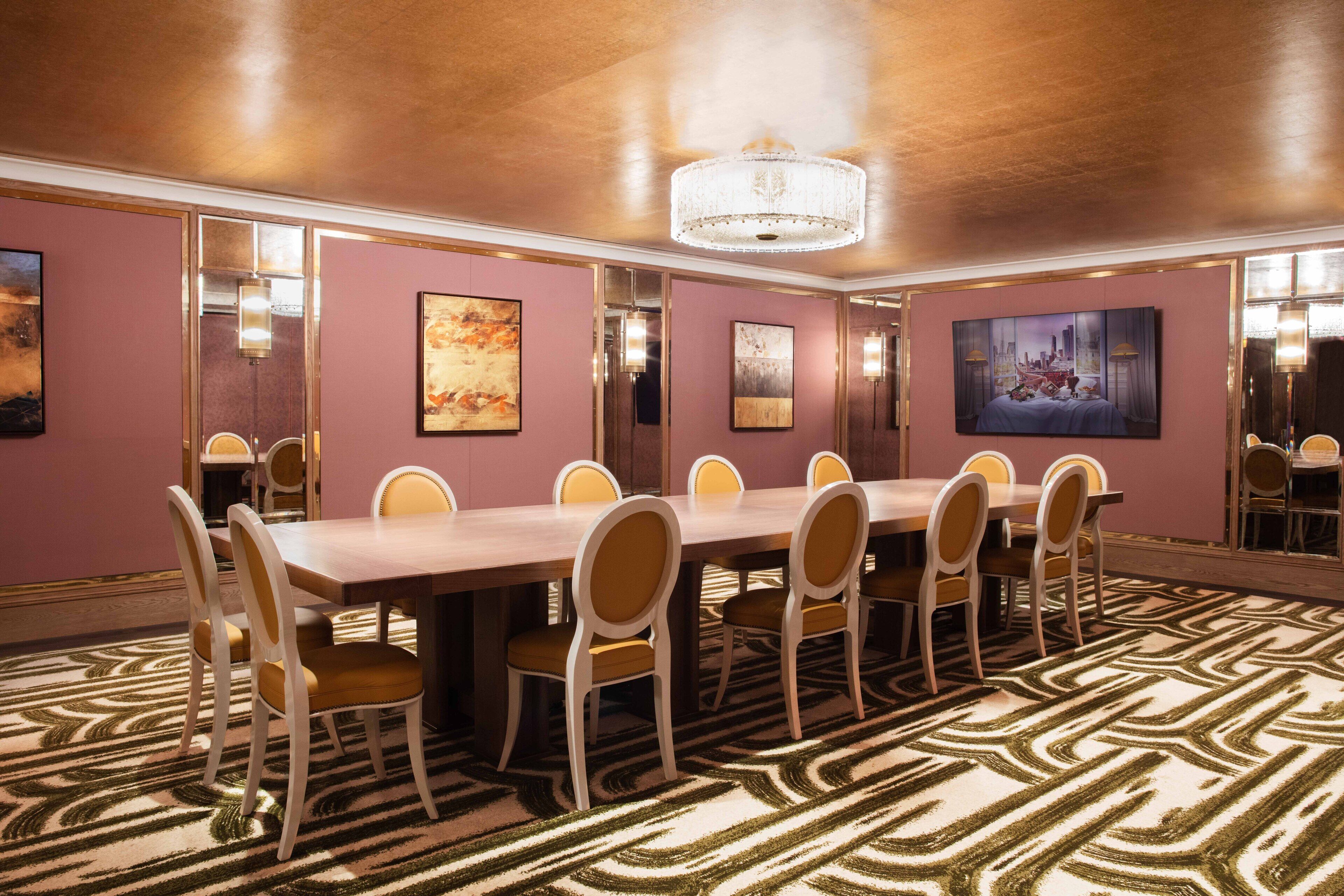 A conference room with a long table, chairs, and artwork on the walls.