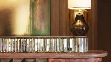 A reception desk with a decorative mirror, a lamp, and a large abstract painting on the wall.