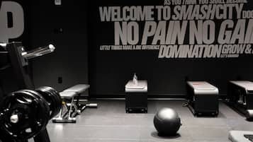 A gym with exercise equipment, benches, and motivational wall text.