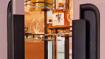 A bar area with a liquor bottle, glasses, and a coffee machine.