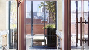 Un interior moderno con un amplio ventanal corredera que da a un balcón exterior con suelo de baldosas y una planta en maceta.