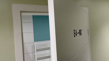 A room with a white door, a teal accent wall, and a white radiator.