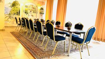 A dining area with a long table, chairs, and a rug.