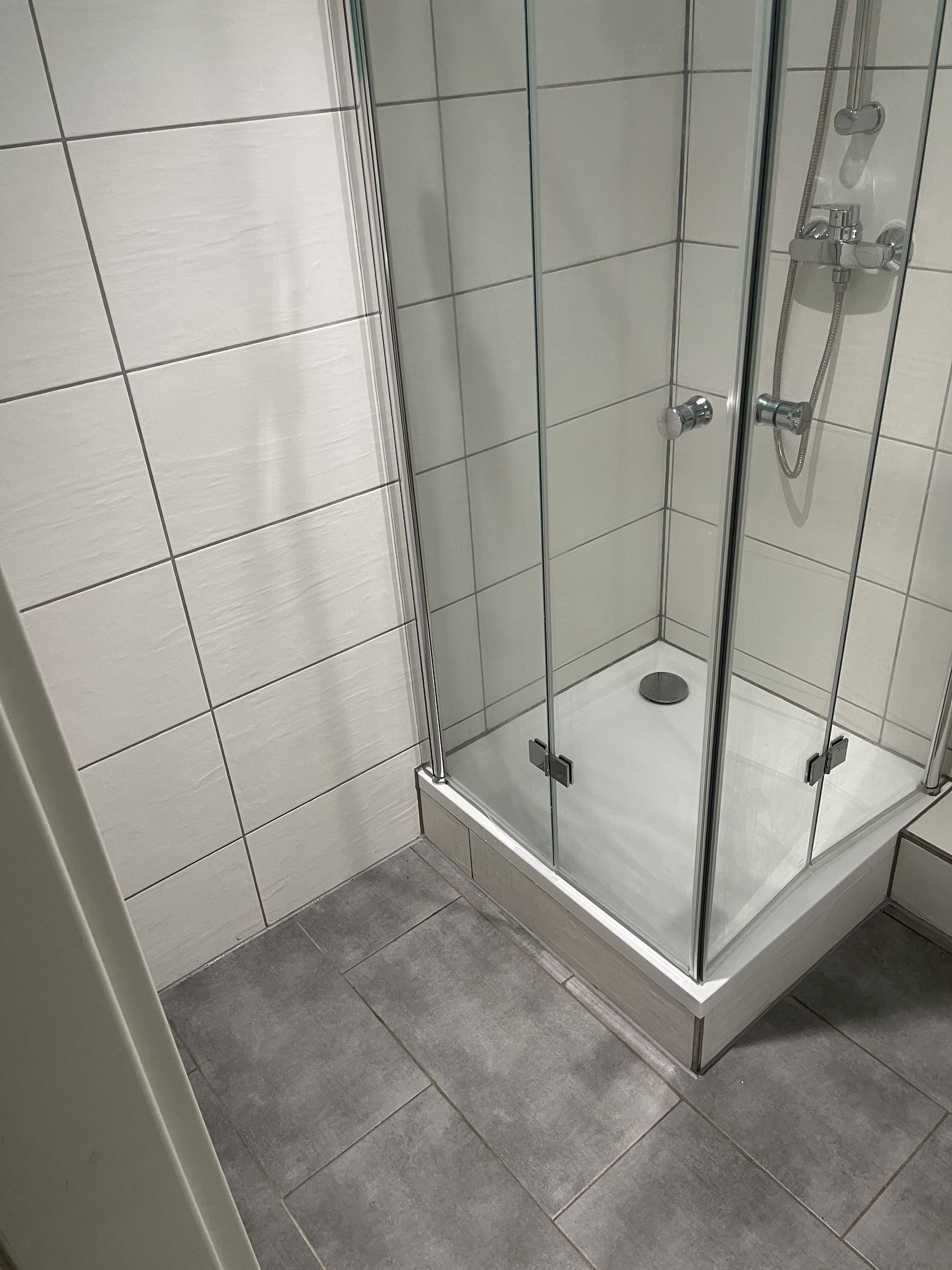 A glass-enclosed shower with a tiled floor and walls.