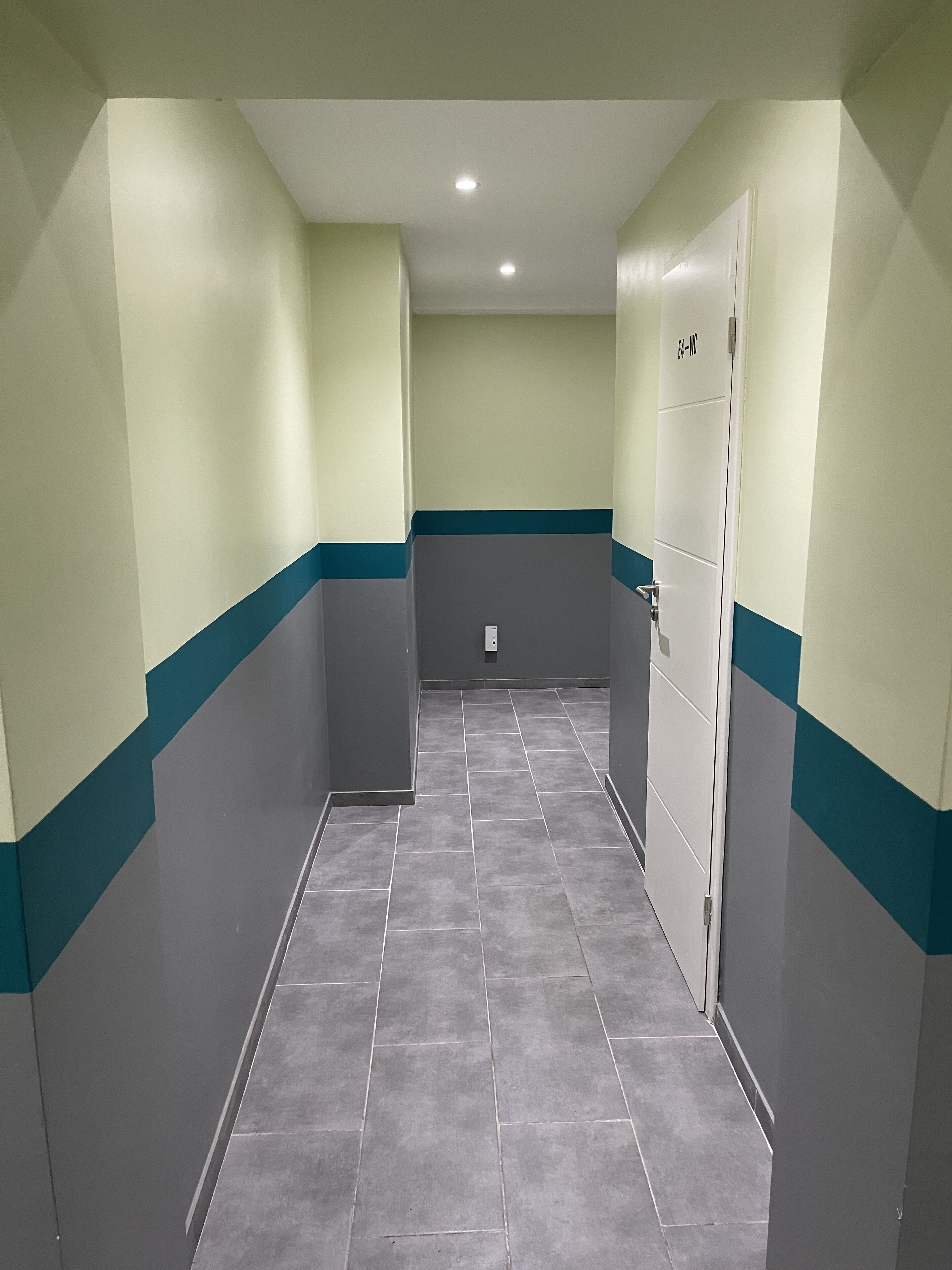 A narrow hallway with tiled flooring and walls painted in two-tone colors.