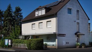 A two-story building with a flat roof, large windows, and a sign indicating it is a 'Fremdenzimmer' (guest room). - Pension Waldau (Kassel)