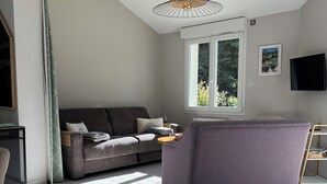 Una sala moderna con un sofá gris, un sillón púrpura y una lámpara colgante.