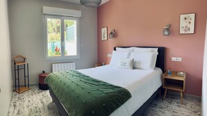 Un dormitorio con cama, mesitas de noche, ventana y lámpara colgante.