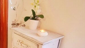 Un mueble de esquina con cajones etiquetados como 'Home', 'Life' y 'Love'. Una planta en maceta y una vela están sobre él.