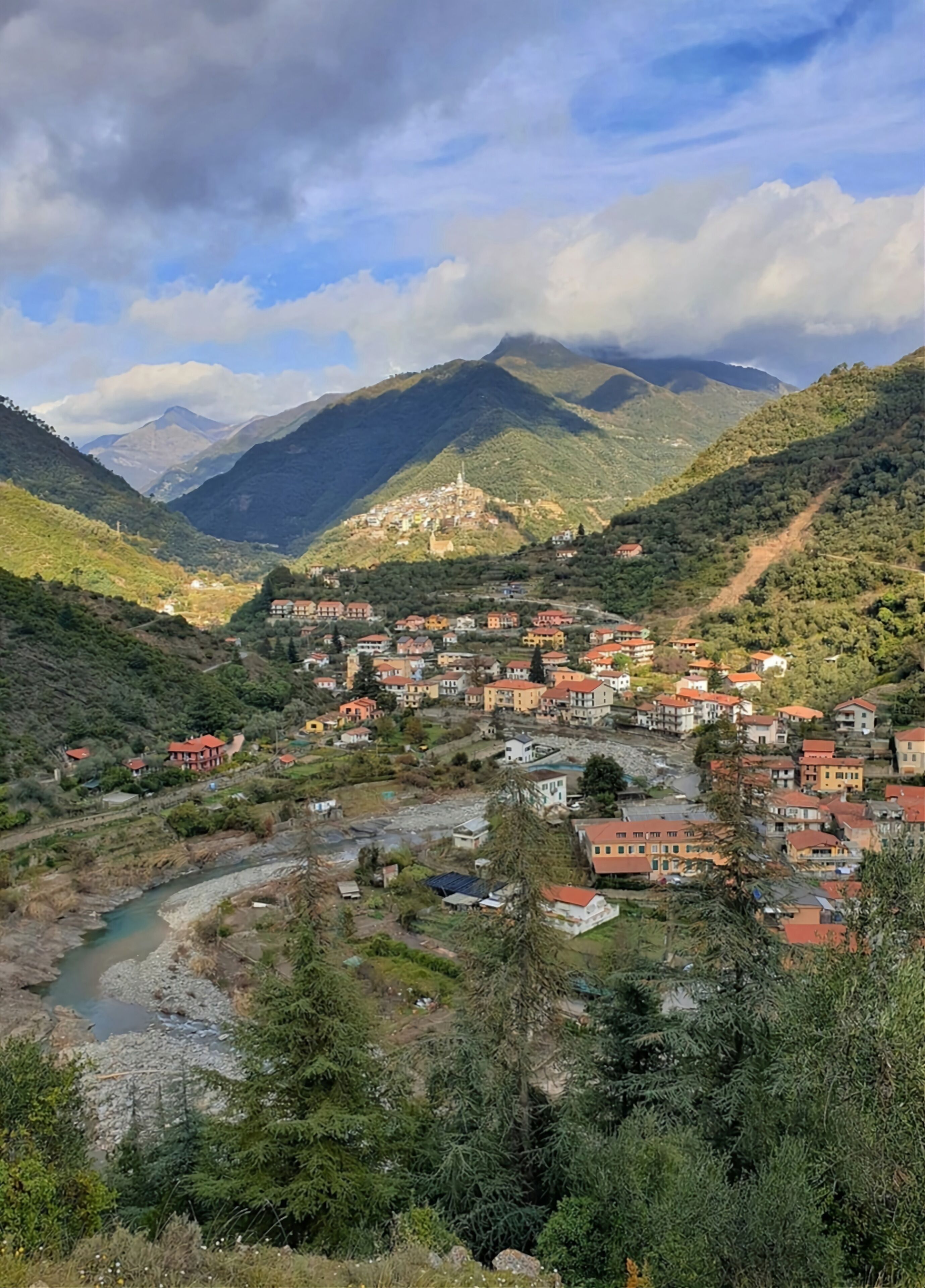 A mountainous town with a river, surrounded by lush greenery and hills.