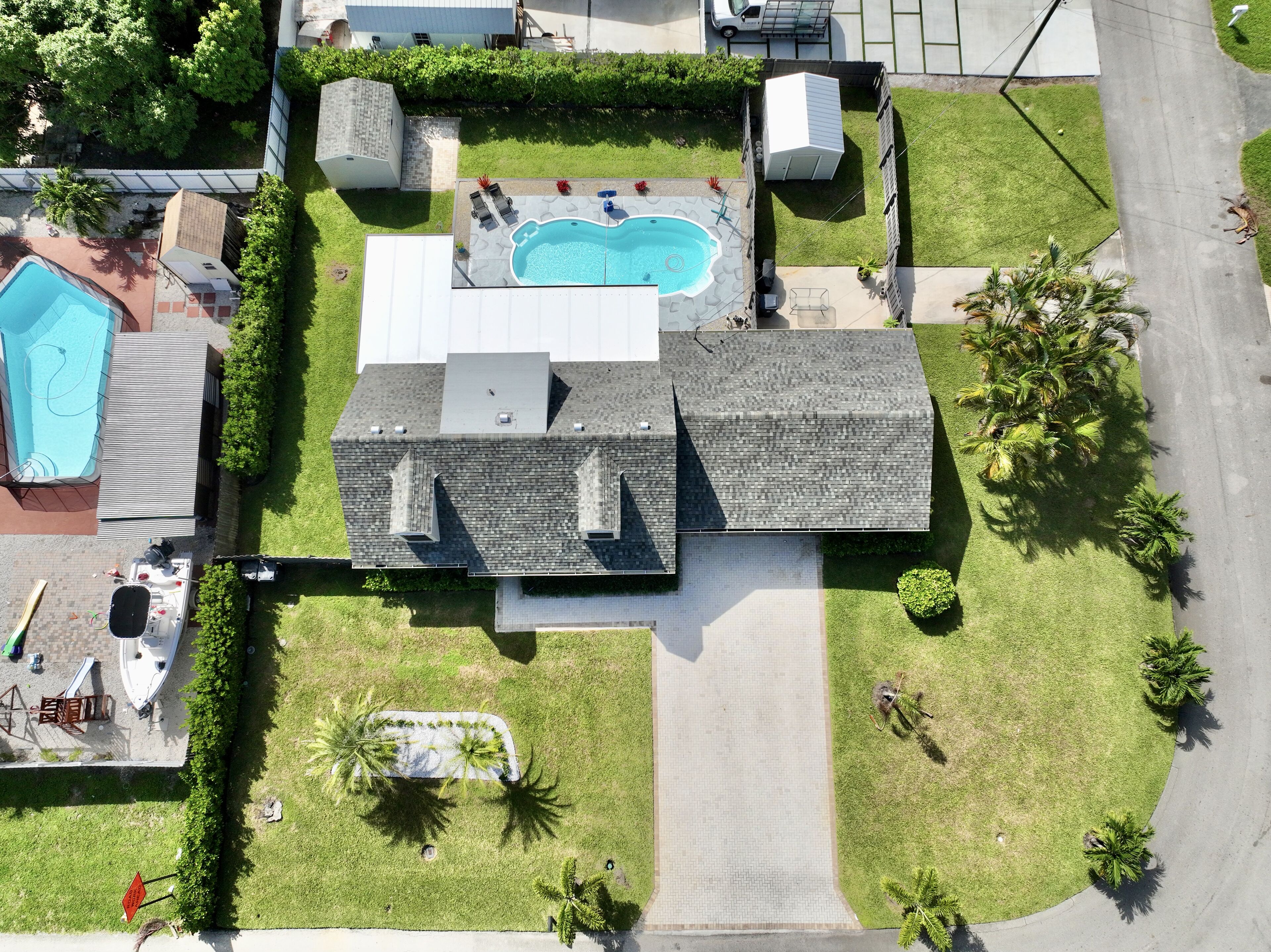 Vista aérea de una propiedad residencial con piscina, terraza cubierta y garaje.
